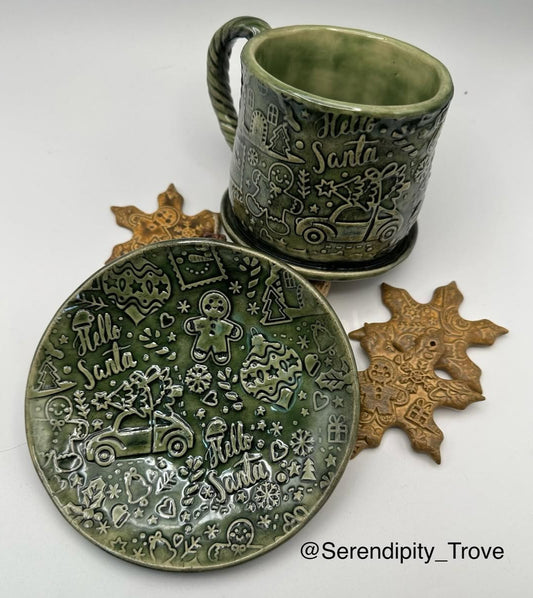 Green ceramic mug and plate with 'Hello Santa' text and winter-themed designs on a white background.